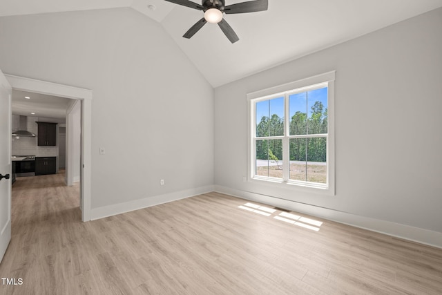 unfurnished room featuring baseboards, a ceiling fan, light wood-style flooring, and high vaulted ceiling