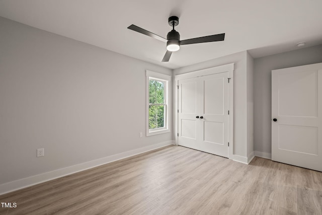 unfurnished bedroom featuring a ceiling fan, baseboards, light wood-style flooring, and a closet