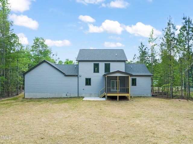 rear view of property with a lawn, roof with shingles, and a sunroom