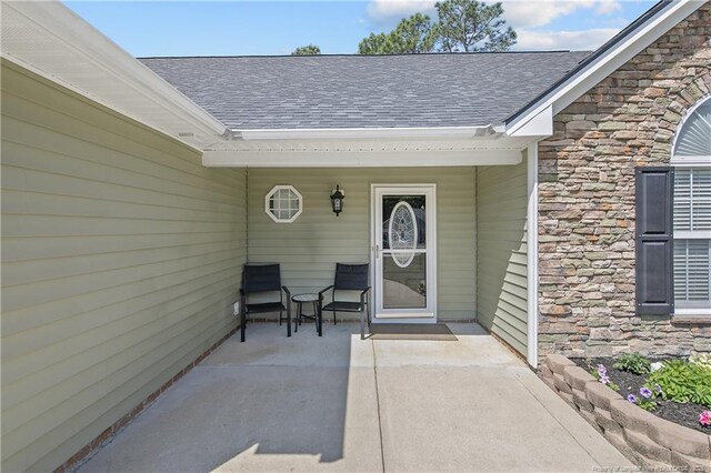 doorway to property with roof with shingles and stone siding