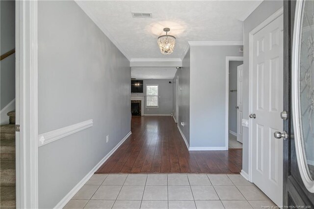 corridor with a notable chandelier, light wood-style flooring, stairs, baseboards, and visible vents