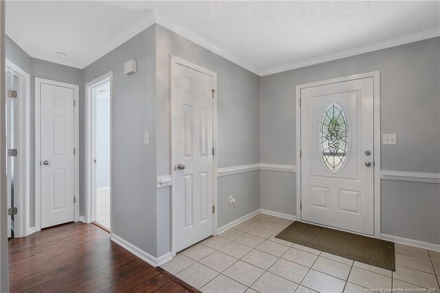 foyer with baseboards, crown molding, and light tile patterned floors
