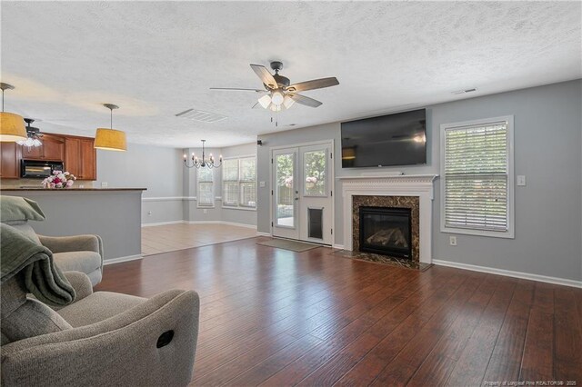 living area featuring a healthy amount of sunlight, baseboards, and ceiling fan with notable chandelier