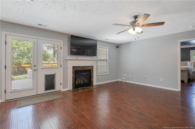 unfurnished living room with visible vents, a ceiling fan, plenty of natural light, and hardwood / wood-style flooring
