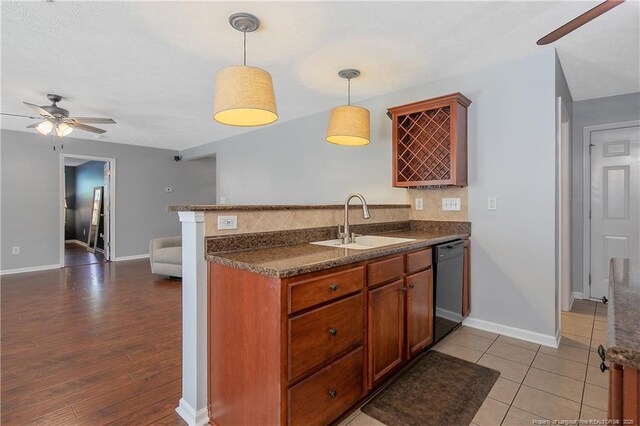 kitchen featuring a ceiling fan, pendant lighting, dark countertops, dishwasher, and a sink