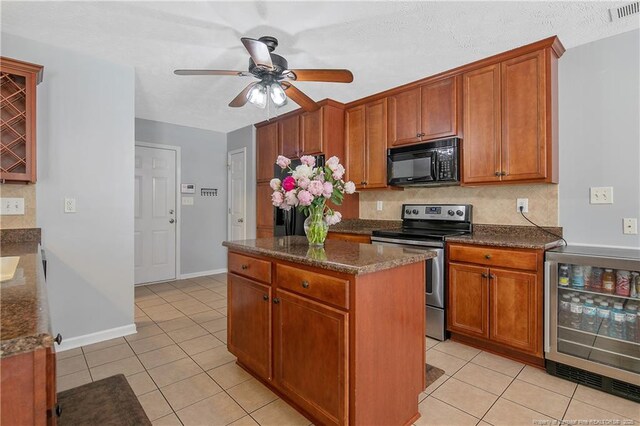 kitchen featuring black microwave, stainless steel range with electric stovetop, light tile patterned floors, wine cooler, and visible vents