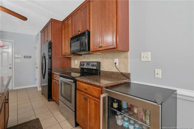 kitchen featuring dark countertops, brown cabinetry, decorative backsplash, light tile patterned floors, and black appliances