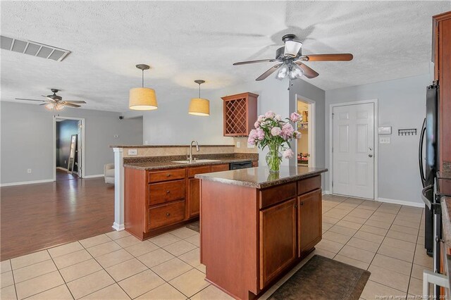 kitchen featuring visible vents, a peninsula, ceiling fan, a sink, and light tile patterned floors