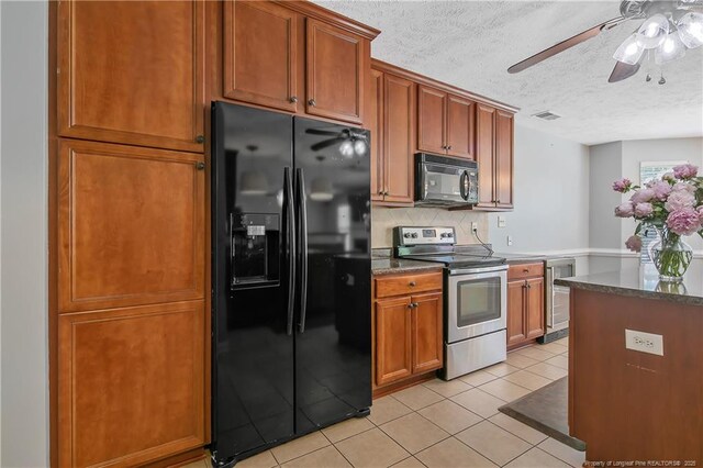 kitchen with a textured ceiling, black appliances, beverage cooler, and visible vents