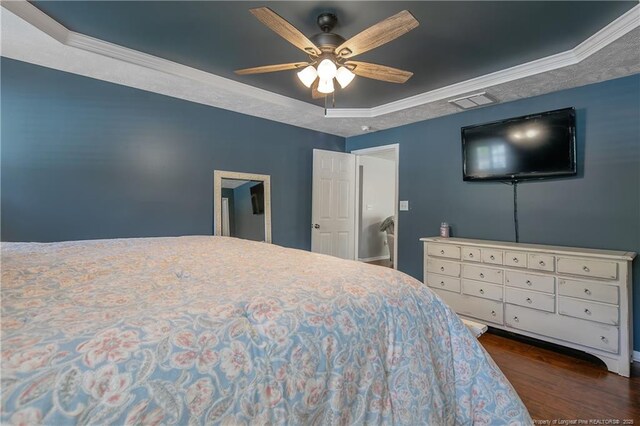 bedroom with crown molding, a raised ceiling, ceiling fan, and dark wood-style flooring