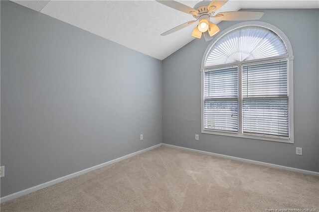 carpeted spare room featuring baseboards, ceiling fan, and vaulted ceiling