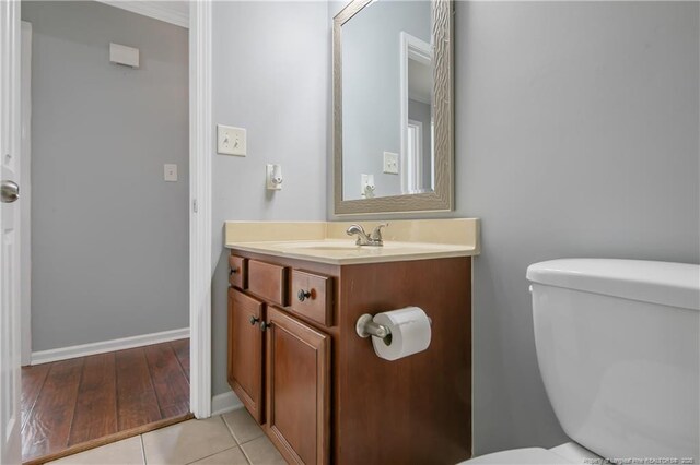 half bathroom featuring toilet, baseboards, tile patterned floors, and vanity