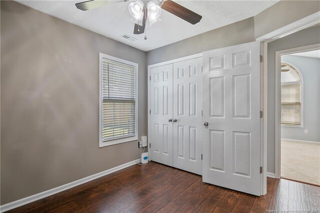 unfurnished bedroom with baseboards, a closet, dark wood-style flooring, and visible vents