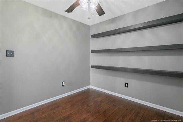 unfurnished room with baseboards, a ceiling fan, and dark wood finished floors