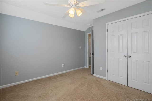 unfurnished bedroom featuring visible vents, a closet, light carpet, baseboards, and a ceiling fan