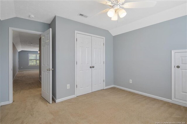 unfurnished bedroom featuring visible vents, baseboards, lofted ceiling, and light carpet