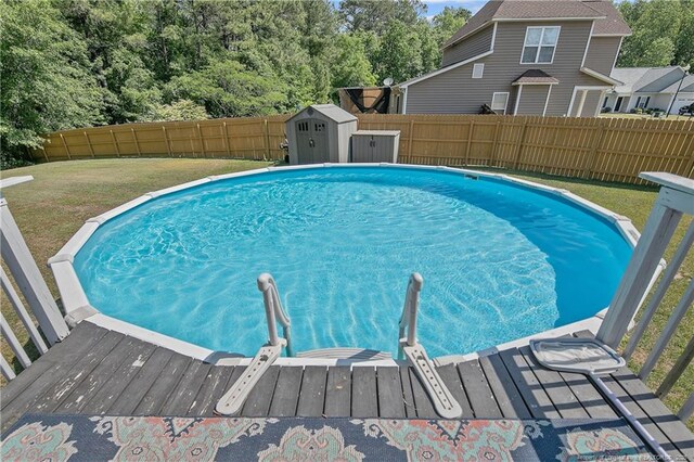 view of swimming pool with an outbuilding, a fenced in pool, a shed, a fenced backyard, and a yard