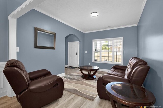 living room featuring light wood-type flooring, ornamental molding, baseboards, and arched walkways