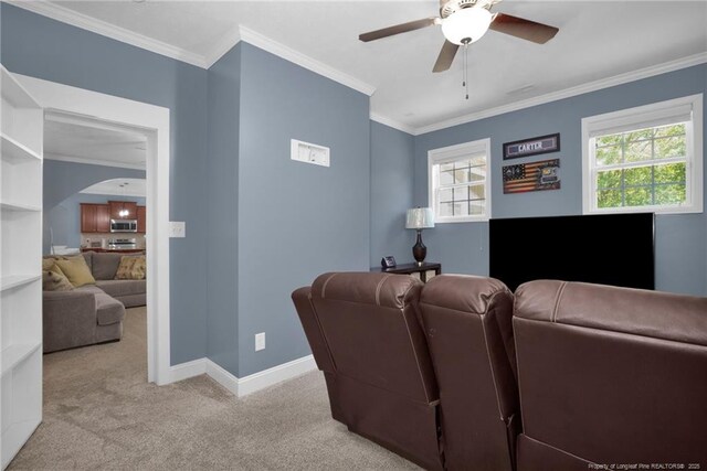 carpeted cinema featuring baseboards, a ceiling fan, arched walkways, and ornamental molding