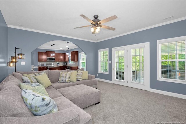 living area with arched walkways, baseboards, a ceiling fan, and plenty of natural light