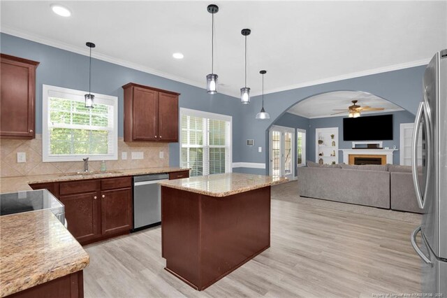 kitchen with ceiling fan, a sink, light wood finished floors, arched walkways, and stainless steel appliances