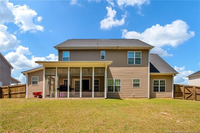 rear view of house featuring a lawn, a fenced backyard, and a sunroom