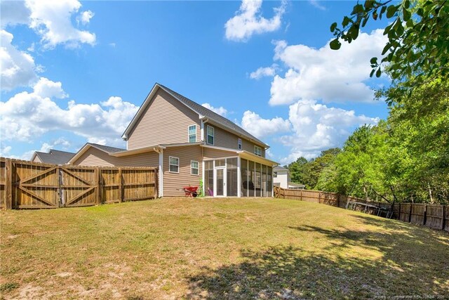back of house with a yard, a gate, a fenced backyard, and a sunroom
