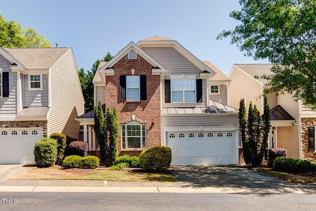 traditional-style house featuring a standing seam roof, metal roof, brick siding, and aphalt driveway