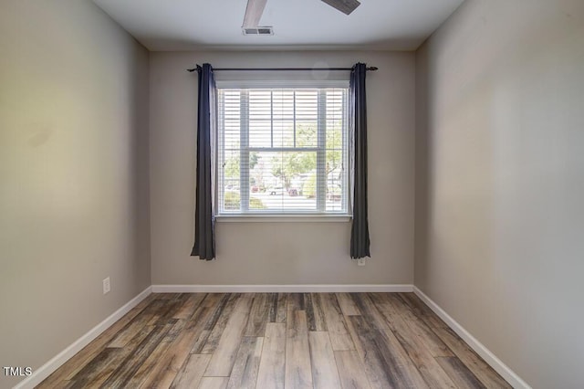empty room featuring baseboards, visible vents, and wood finished floors