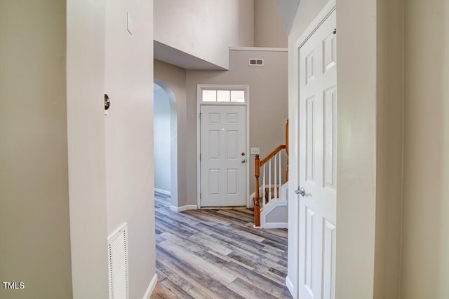 entryway with arched walkways, baseboards, visible vents, and light wood-type flooring