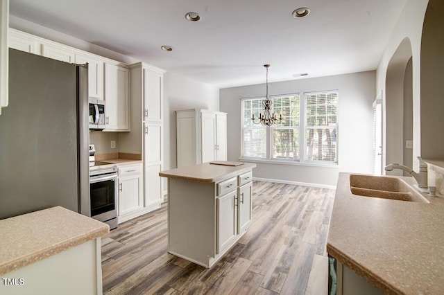 kitchen with a sink, arched walkways, light wood-style floors, and stainless steel appliances