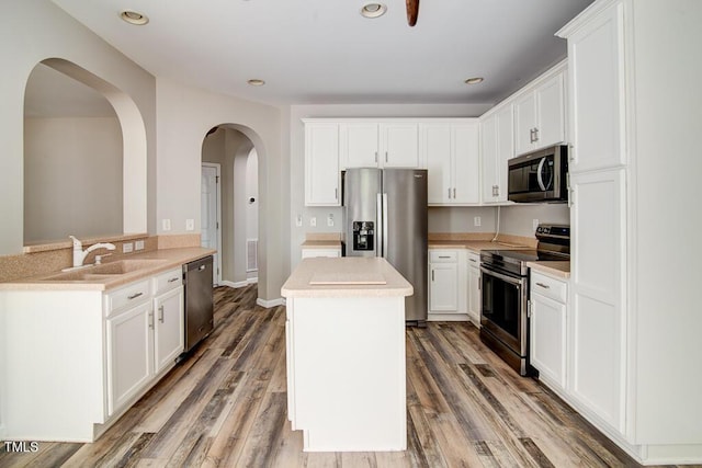 kitchen with a center island, a sink, light countertops, light wood finished floors, and stainless steel appliances