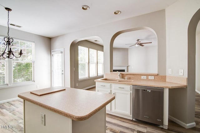 kitchen featuring stainless steel dishwasher, arched walkways, light wood-style flooring, and ceiling fan with notable chandelier