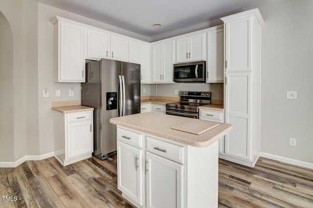 kitchen featuring baseboards, light countertops, appliances with stainless steel finishes, and wood finished floors