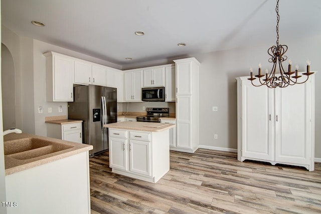 kitchen featuring light countertops, white cabinets, a sink, light wood-style flooring, and stainless steel appliances