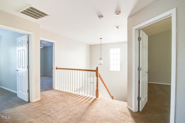 corridor featuring visible vents, carpet, baseboards, and an upstairs landing