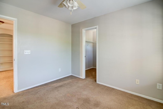unfurnished bedroom with ceiling fan, carpet, baseboards, a spacious closet, and a closet