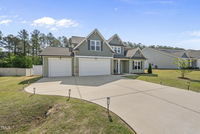 craftsman-style home featuring fence, stone siding, a garage, a front yard, and concrete driveway