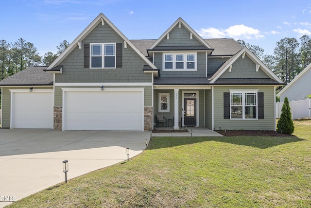 craftsman inspired home featuring covered porch, an attached garage, driveway, and a front yard