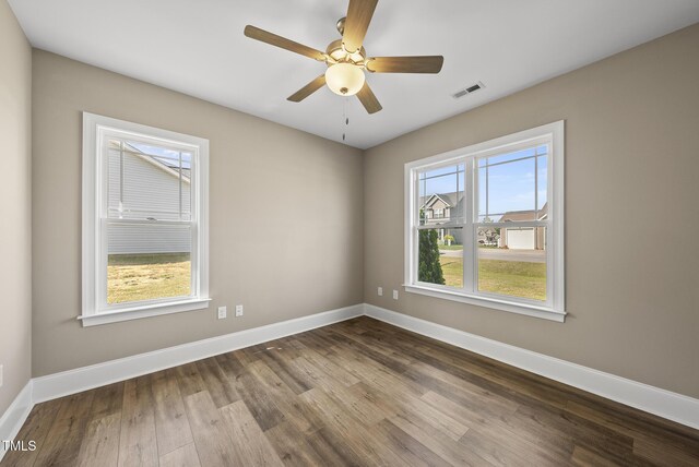 unfurnished room featuring baseboards, dark wood finished floors, and visible vents