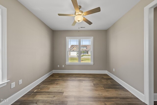 unfurnished room featuring a ceiling fan, baseboards, visible vents, and dark wood-style floors