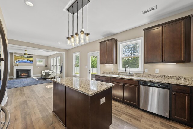 kitchen featuring a kitchen island, stainless steel dishwasher, dark brown cabinets, a sink, and open floor plan