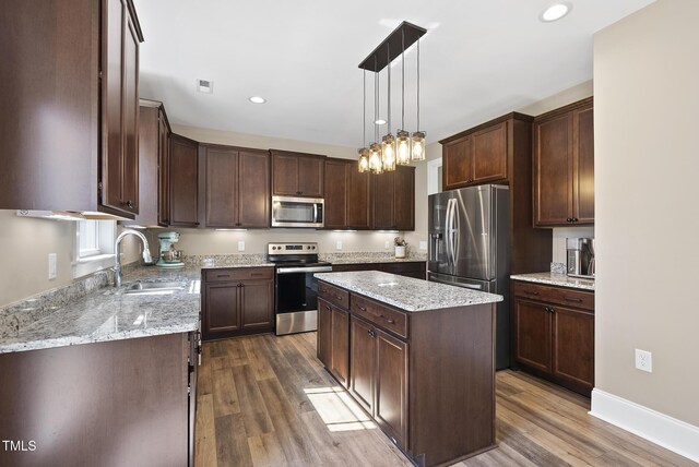 kitchen with dark brown cabinets, a center island, a sink, dark wood finished floors, and stainless steel appliances