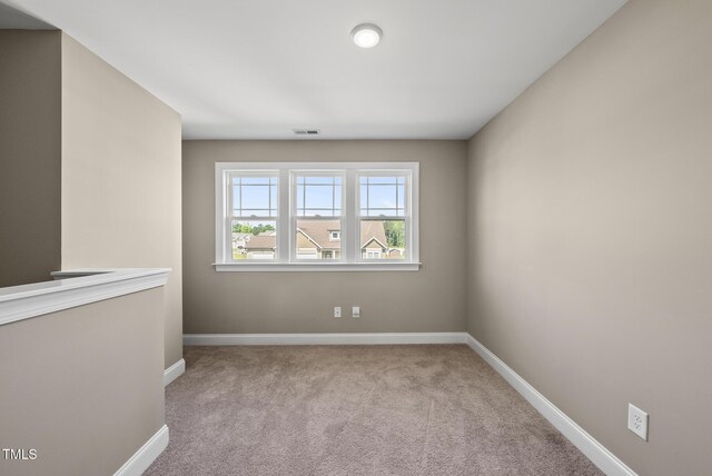 carpeted spare room with baseboards and visible vents