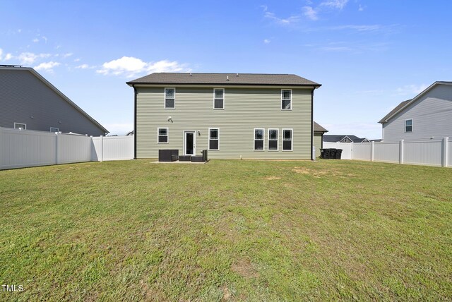 rear view of property with a fenced backyard, a yard, and central AC unit