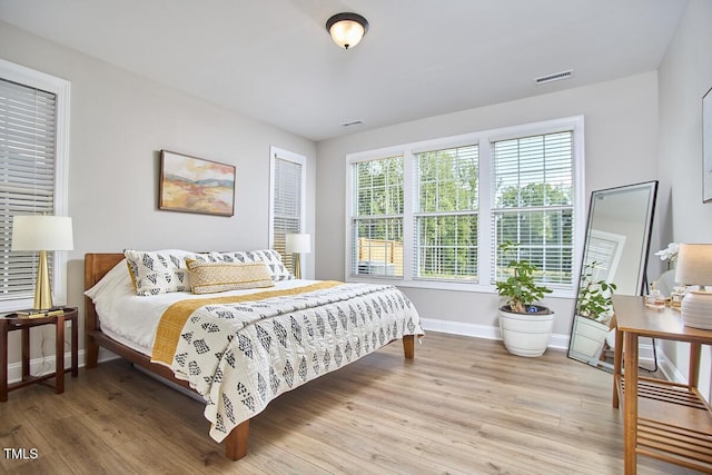 bedroom featuring baseboards, light wood-style flooring, and visible vents