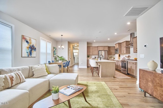 living room with an inviting chandelier, recessed lighting, light wood finished floors, and visible vents