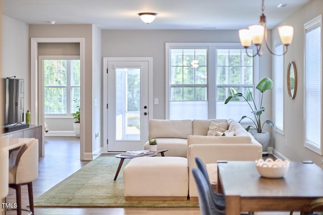 living room featuring baseboards, wood finished floors, and a notable chandelier