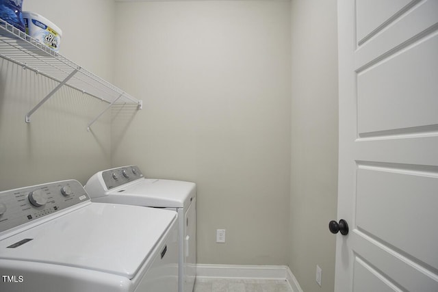 clothes washing area with laundry area, baseboards, and washing machine and dryer