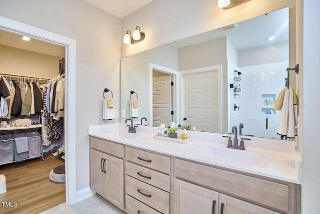 full bathroom with double vanity, a sink, a stall shower, and a spacious closet